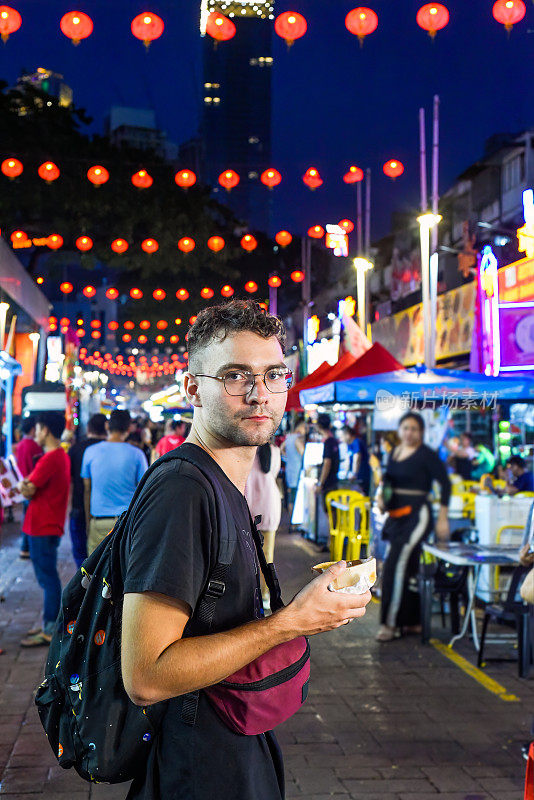 马来西亚吉隆坡，一名年轻游客在Jalan Alor街头小吃店吃冰淇淋